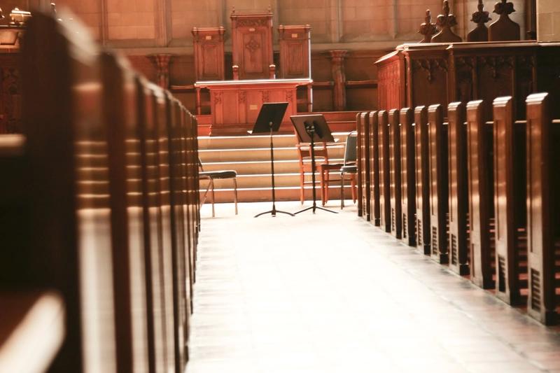 Rows of wooden pews inside a sunlit chapel, with a pulpit in the centre