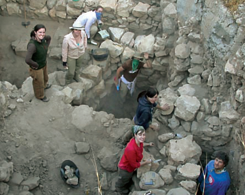 Bird's eye view of U of T field researchers excavating the remains of a building with stone walls.