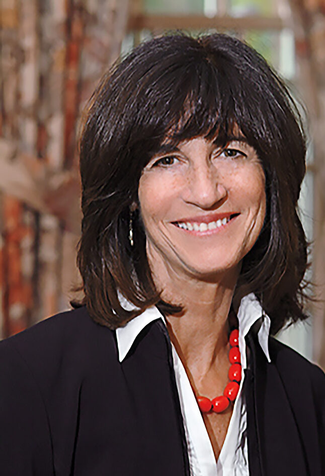 Headshot of Rivi Frankle, wearing a red beaded necklace and a black jacket over a white collared shirt