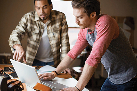 Photo of two men discussing something while looking at a computer screen.