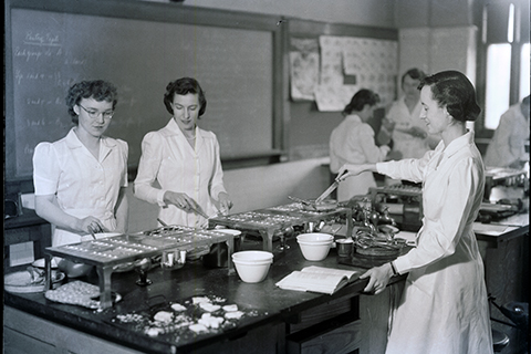 Photo of women at cooking stations in the faculty of household science.