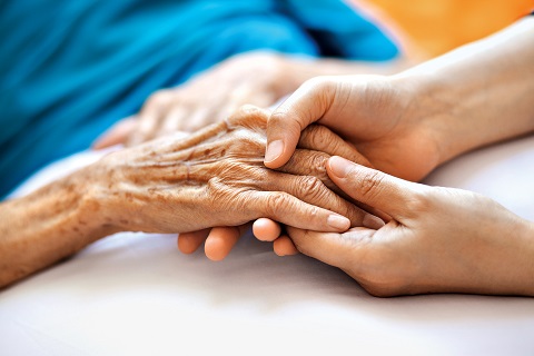 Photo of young hands holding an elderly person's hand.