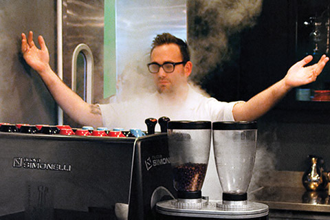 Photo of a man standing with open arms in front of brewing coffee