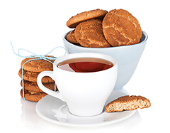 Photo of a cup of tea and cookies in a bowl, on the side and one half eaten