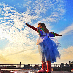 Photo of a girl in a dress and boots with her arms stretched wide