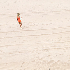 Photo of a girl in an orange bathing suit, running on a beach