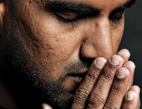 Close-up photo of Shawn Ahmed with his eyes closed and hands joined together