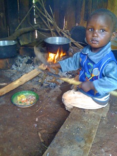 Photo of a child playing in front of a cooking fire