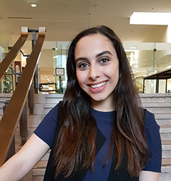 Headshot of Emily Mangialardi on the stairway in the lobby of Gerstein Library.