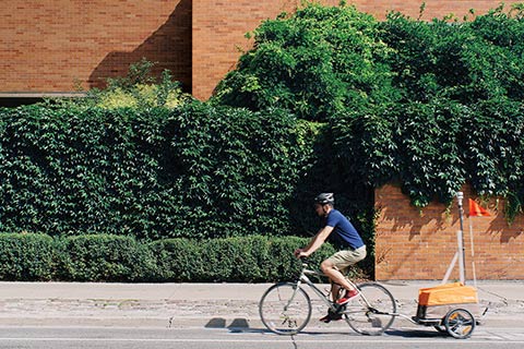 Photo of Colin Arrowsmith biking along Huron Street, pulling a device.