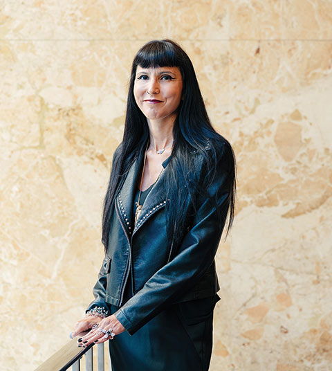 Photo of Prof. Suzanne Stewart standing indoors beside a railing.