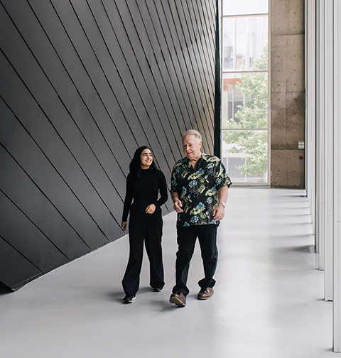 Photo of Ishveer Malhi and Ken Luckhurst walking and conversing inside a UTM building.