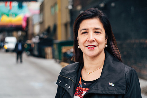 Headshot of Prof. Eileen de Villa standing in the middle of a street