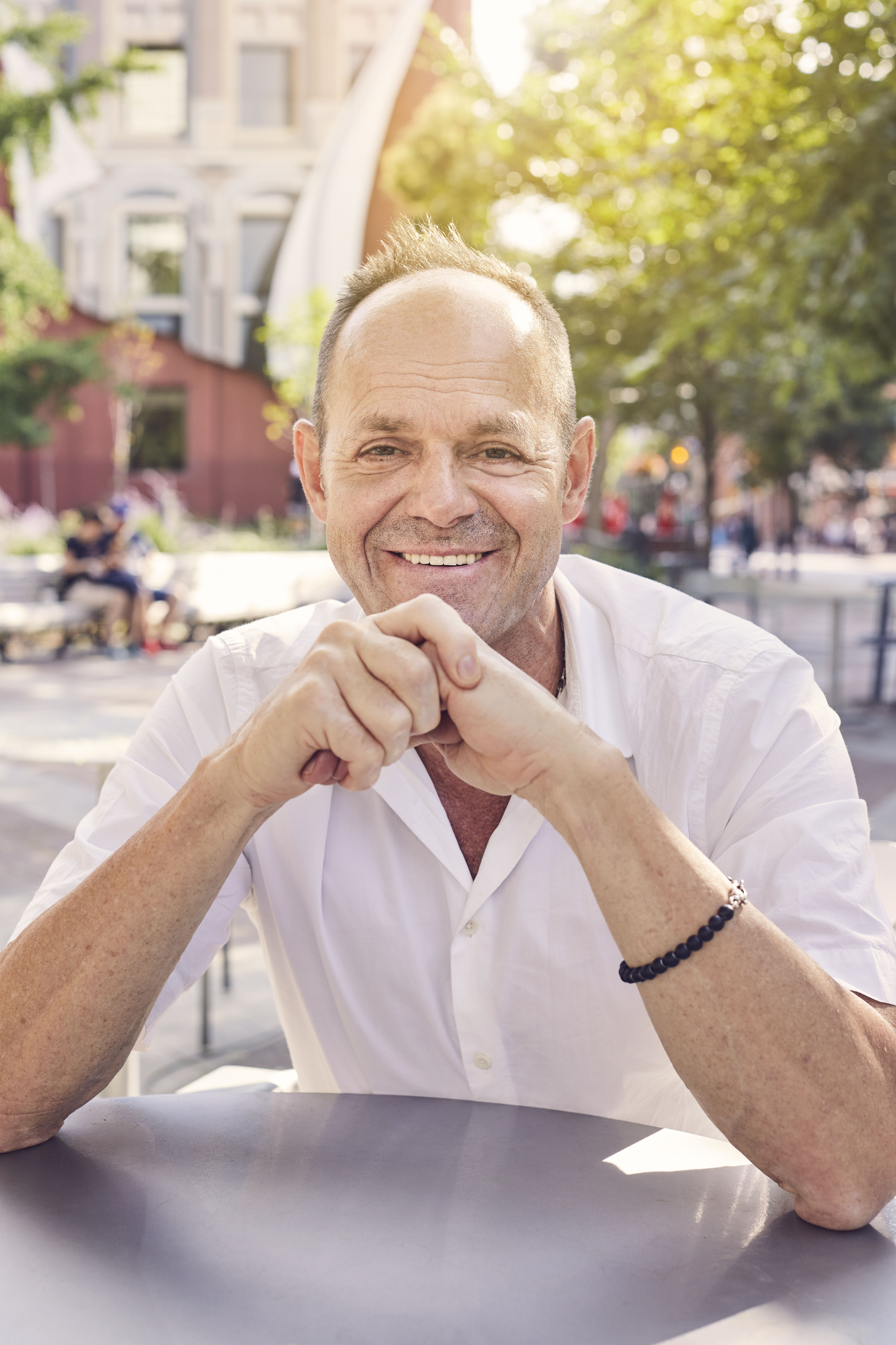 Claude Cormier sitting at table in Berczy Park, Toronto