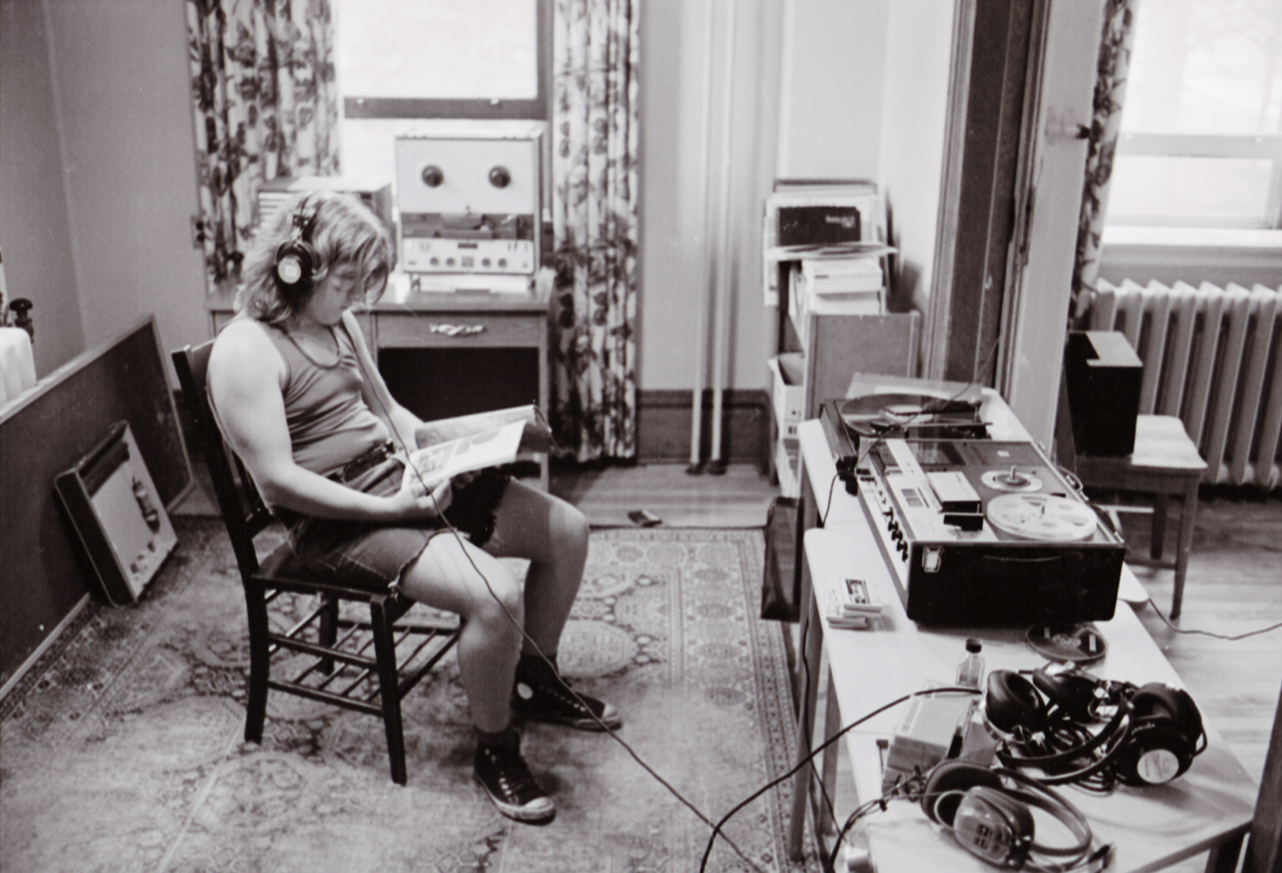 A Cool School student reads alone in a room while listening to something on headphones