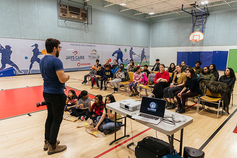 A facilitator addresses an audience of Junior Youth Spiritual Empowerment Program members and children.