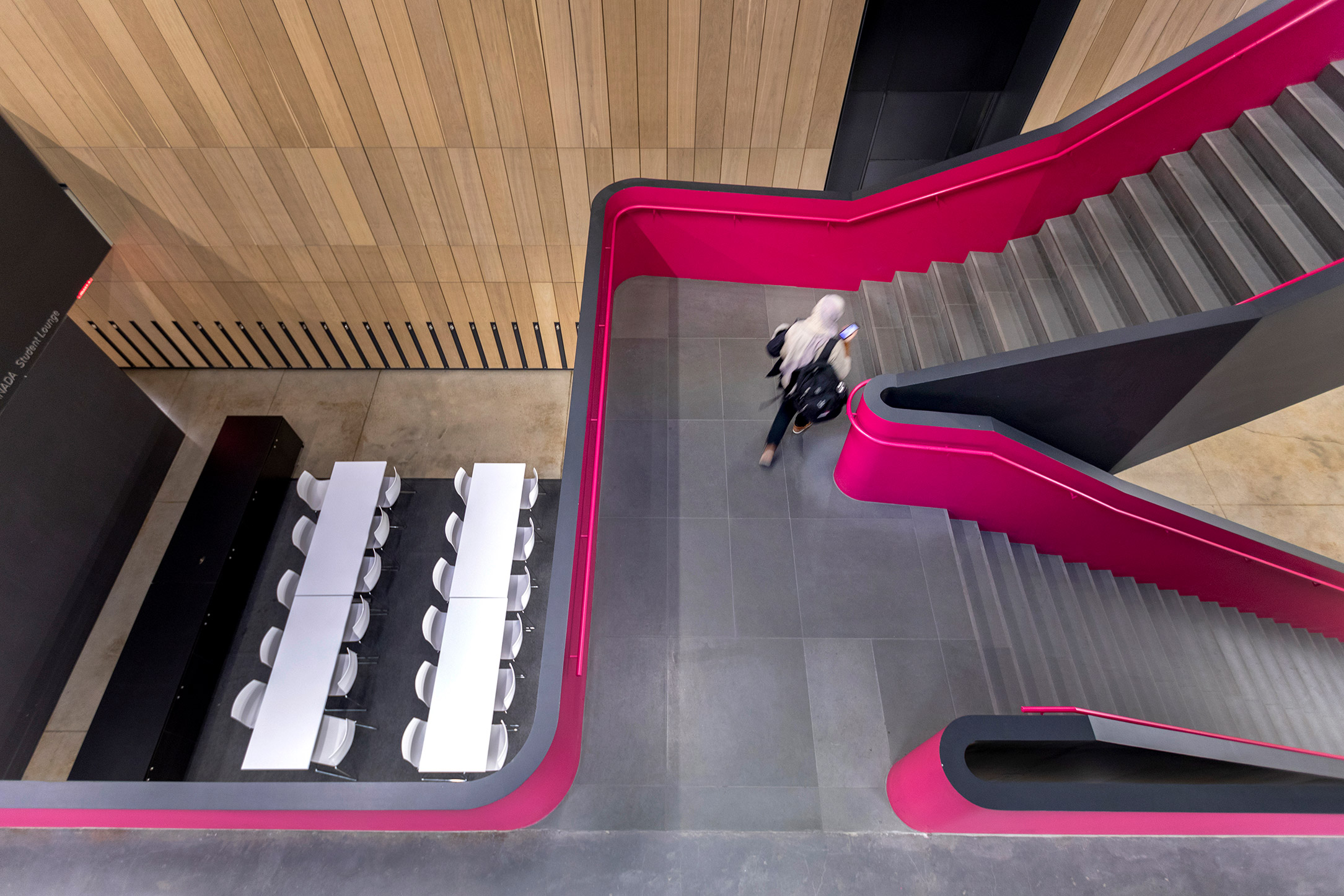 Woman walking up a stairwell in the Rotman School of Management