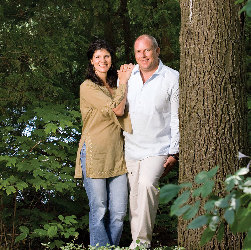 Alessandra and Paul Dalla Lana standing beside a tree with Alessandra's arms clasped around Paul's shoulder