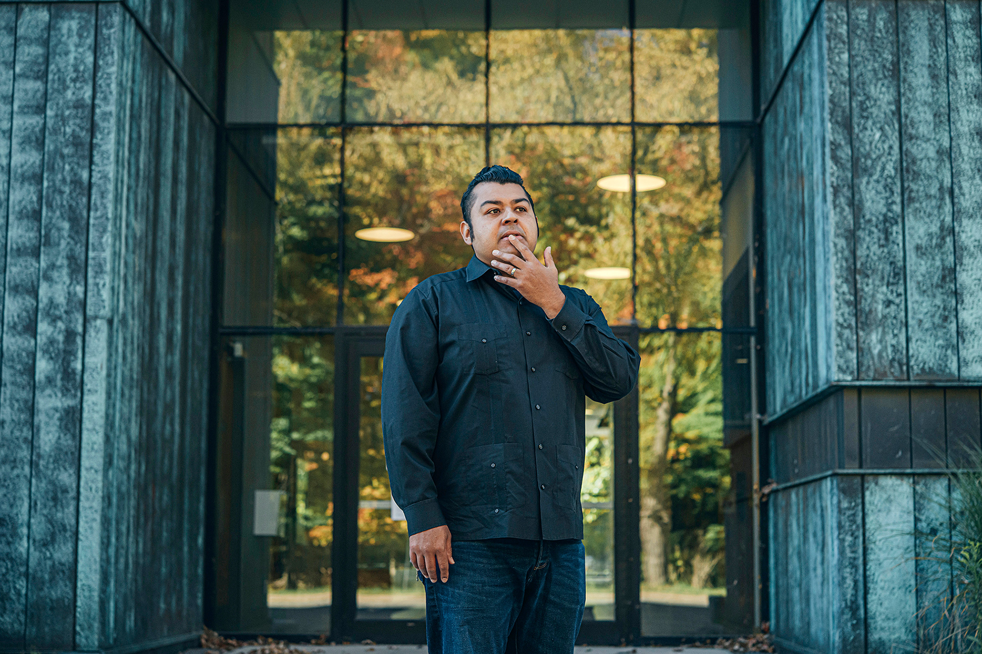 Prof. Jerry Flores standing outside the entrance to a blue walled building