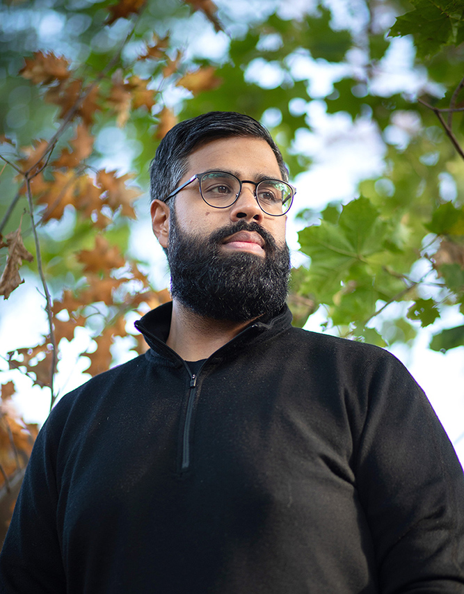 Close up of Satish Kanwar looking off to the side with trees in the background