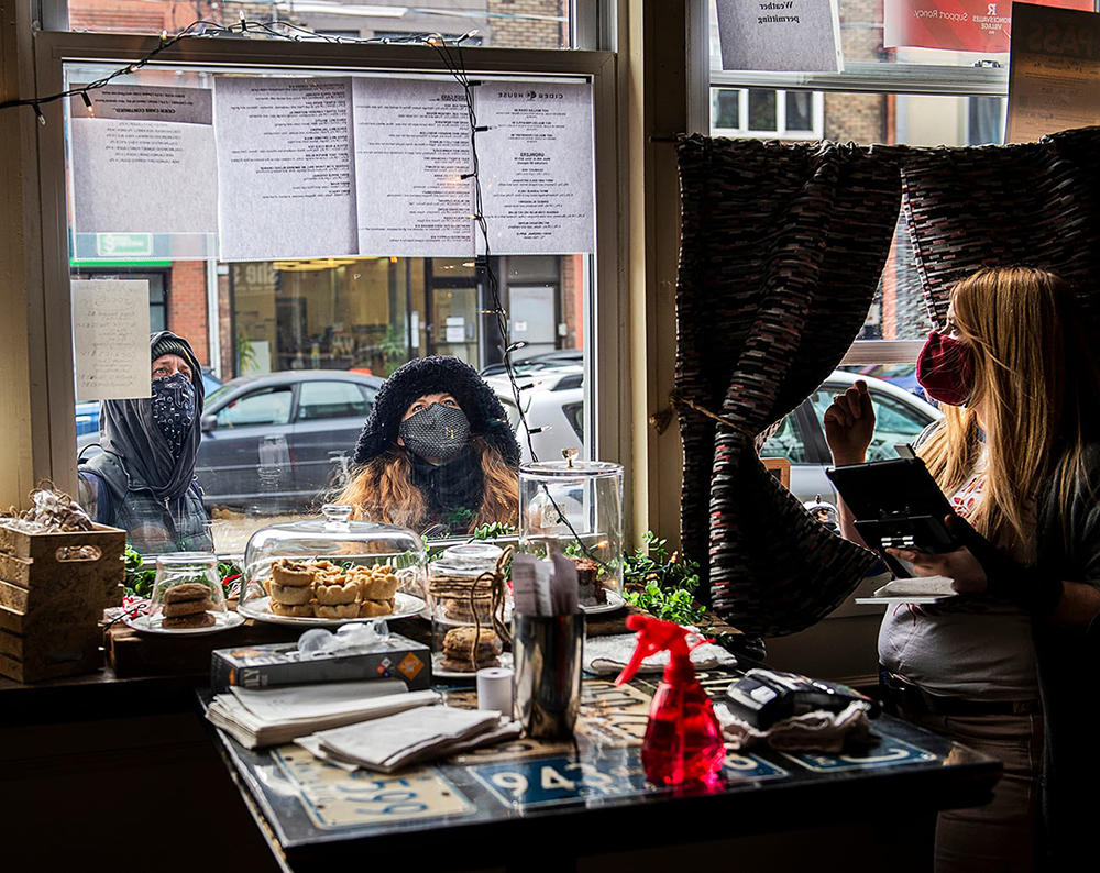 Photo of customers looking at paper menus outside the window of Cider House