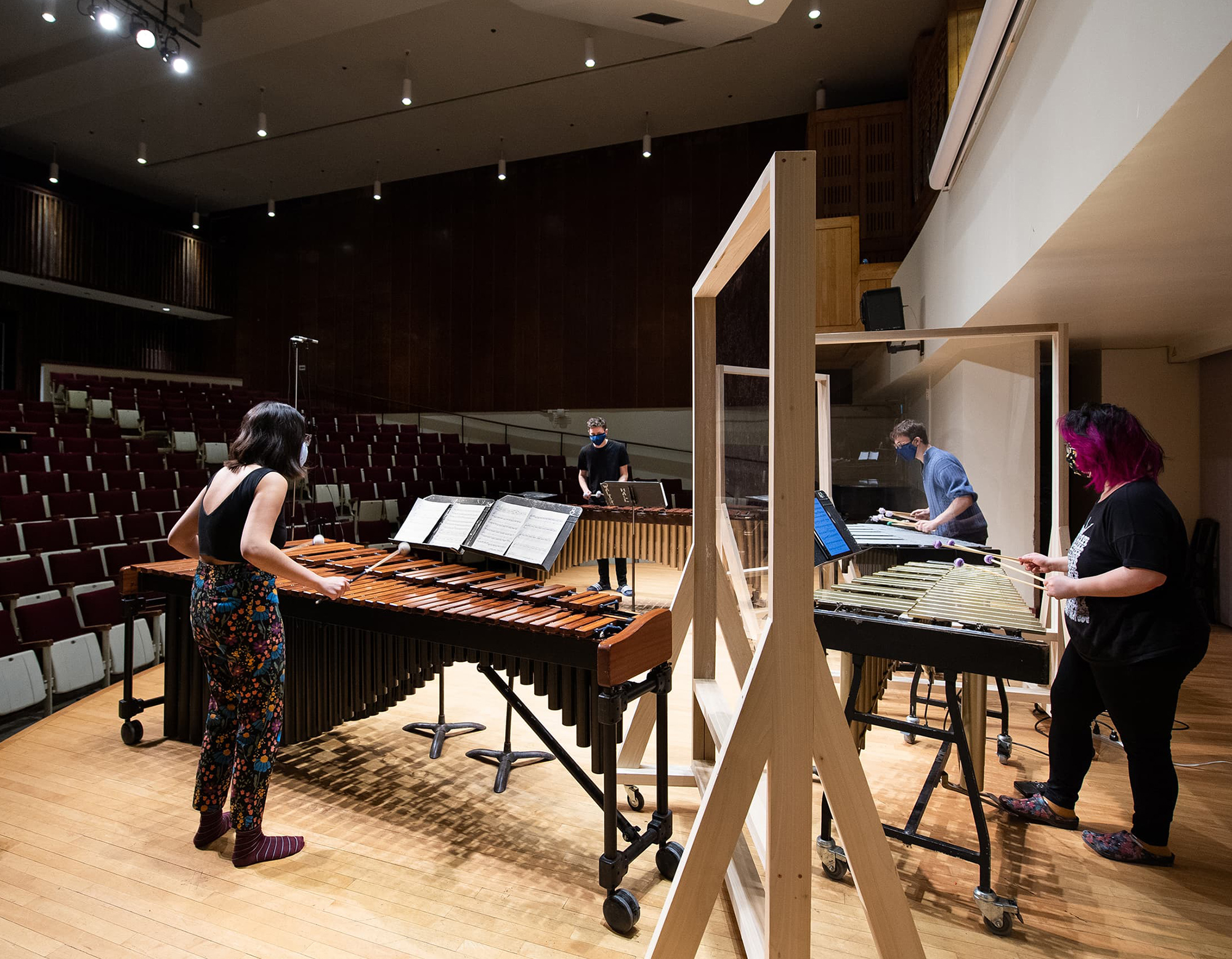 Students rehearsing on their instruments onstage, socially distanced and wearing masks