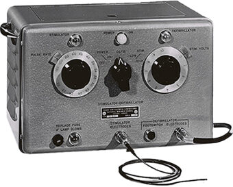 Black and white photo of the first electronic heart pacemaker, a metal box with three black dial in the centre and connectors at the bottom