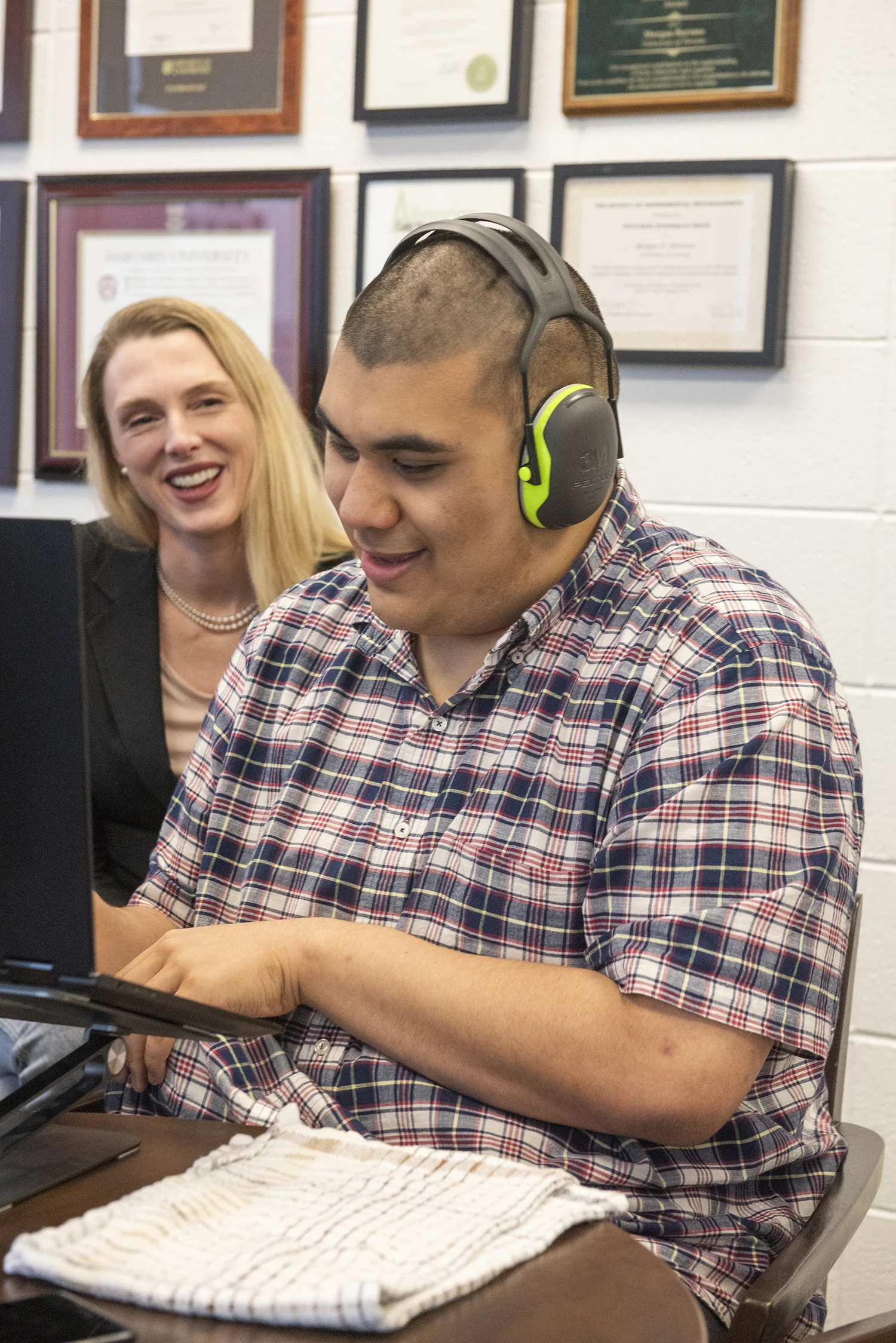 Isaiah Grewal, wearing headphones and typing on a laptop, with Morgan Barense seated next to him, both smiling